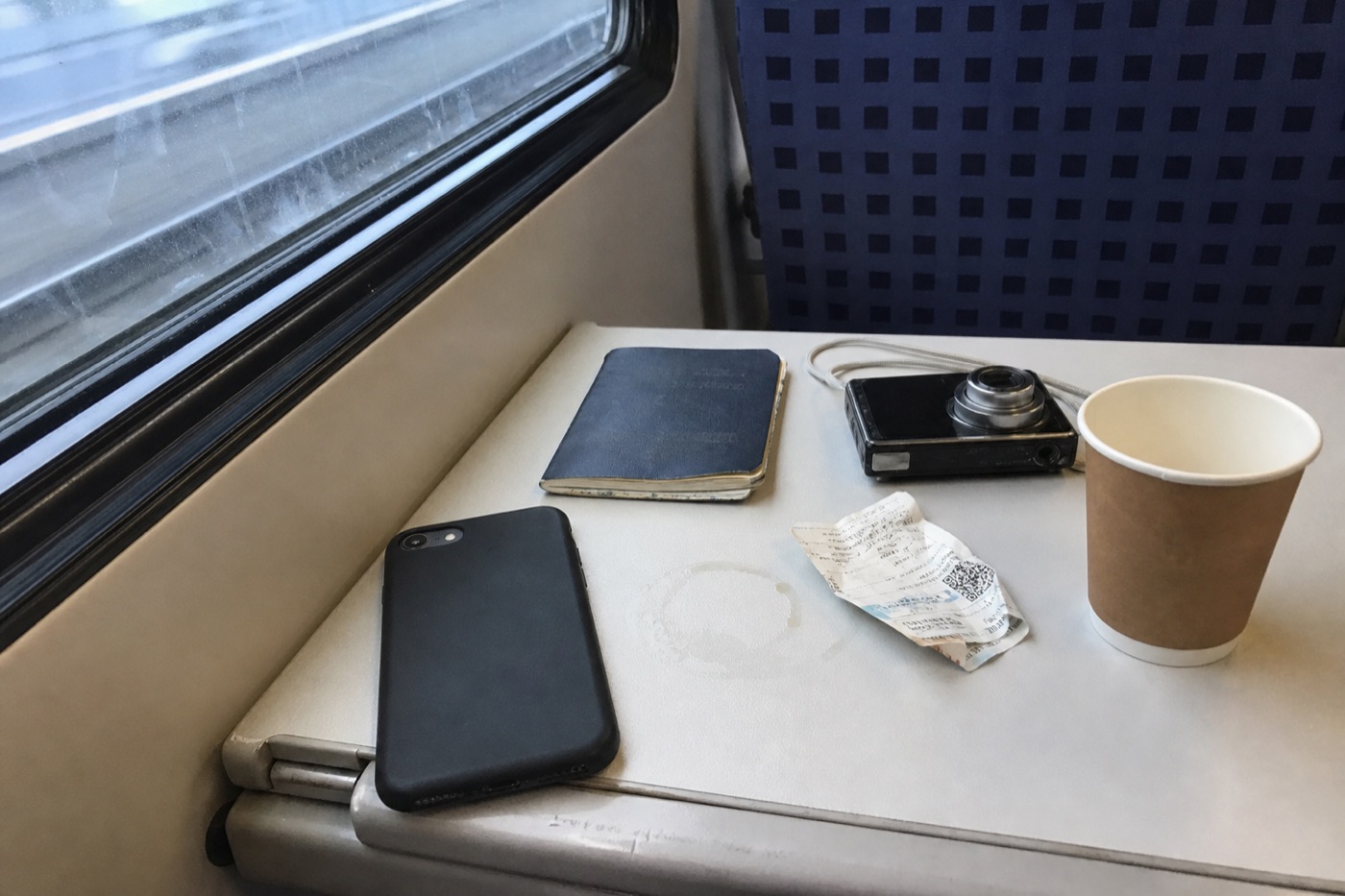 Skládací stolek ve vlaku s obráceným mobilním telefonem, pasem, fotoaparátem a jízdenkou