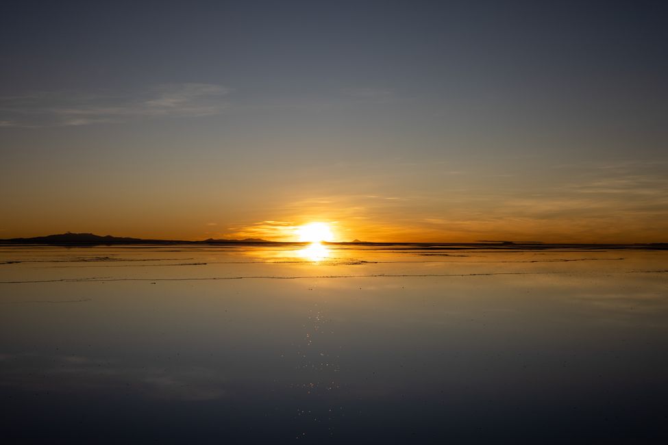 The sun rises over the horizon of the Salar de Uyuni