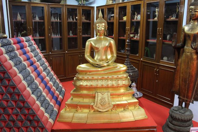 Wat Intharawihan: Buddha collection on cabinet