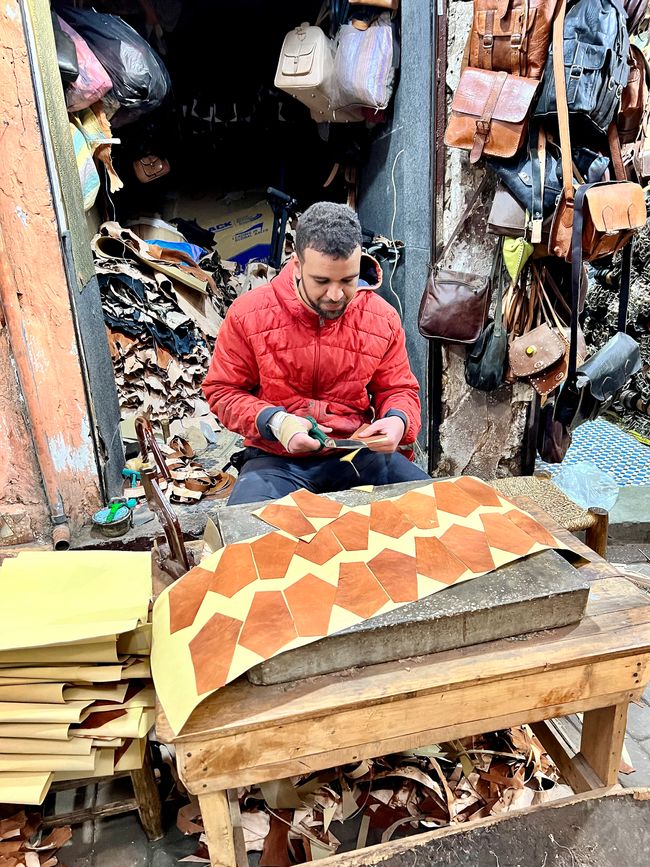 This young man cuts leather for bags.