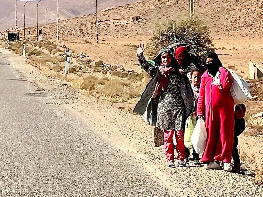 A group of women and children by the roadside.