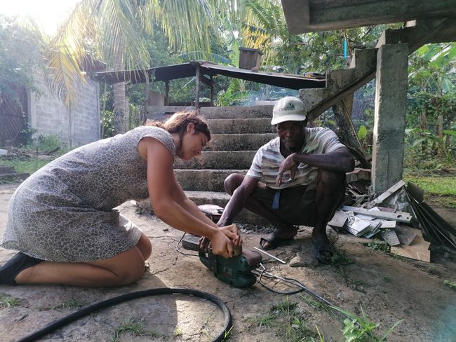 Nina bekommt Unterstützung beim Kokosnuss bearbeiten 