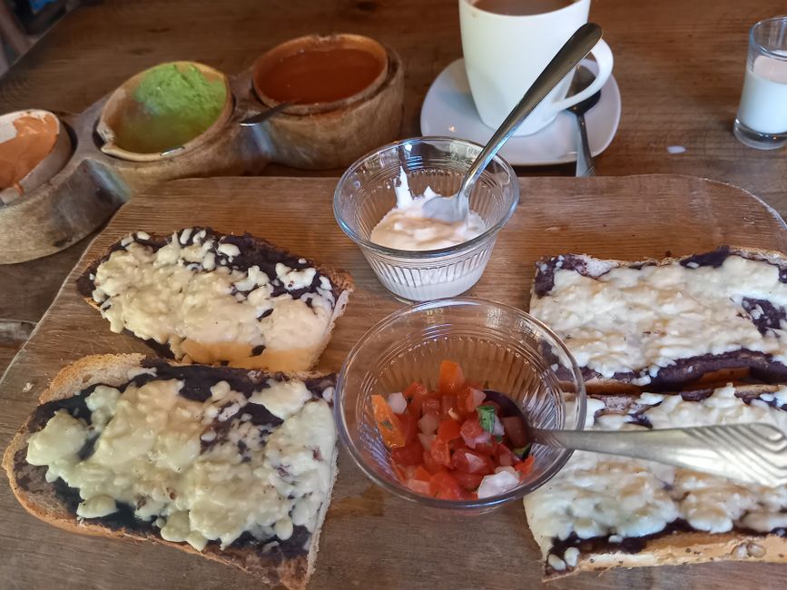 Überbackene Brote mit Bohnenmatsch und Oaxaca-Käse, dazu Salsa und Schmand