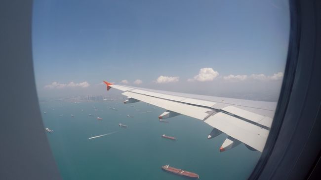 Aus dem Flieger: Anflug auf Singapur, links die Hochhäuser, unten viele Containerschiffe im blauen Wasser