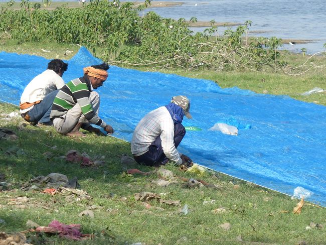 Fishermen mend their nets by the lake
