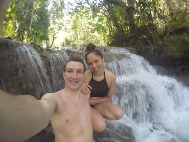 Us sitting in a small waterfall on a big stone at Tad Kuang Si