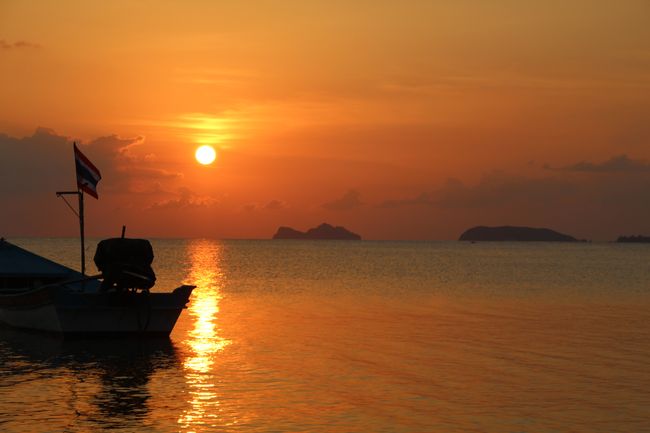 Ein Boot mit thailändischer Flagge vor dem Sonnenuntergang