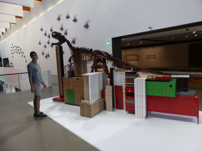 Andi in front of a dinosaur skeleton-Ikea furniture sculpture