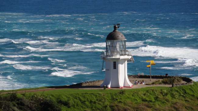 Lighthouse at Cape Reinga. In the background, the stormy sea (here the current of the Tasman Sea meets that of the Pacific Ocean).