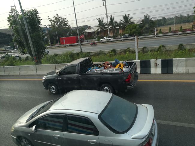Man relaxing in the bed of a pickup truck...while driving...on the highway.