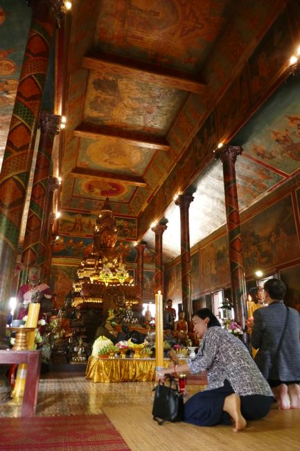 Die Buddhisten beten und beschenken Buddha reichlich: überall auf Tischen und Statuen sind Geldscheine und frisches Essen zu sehen