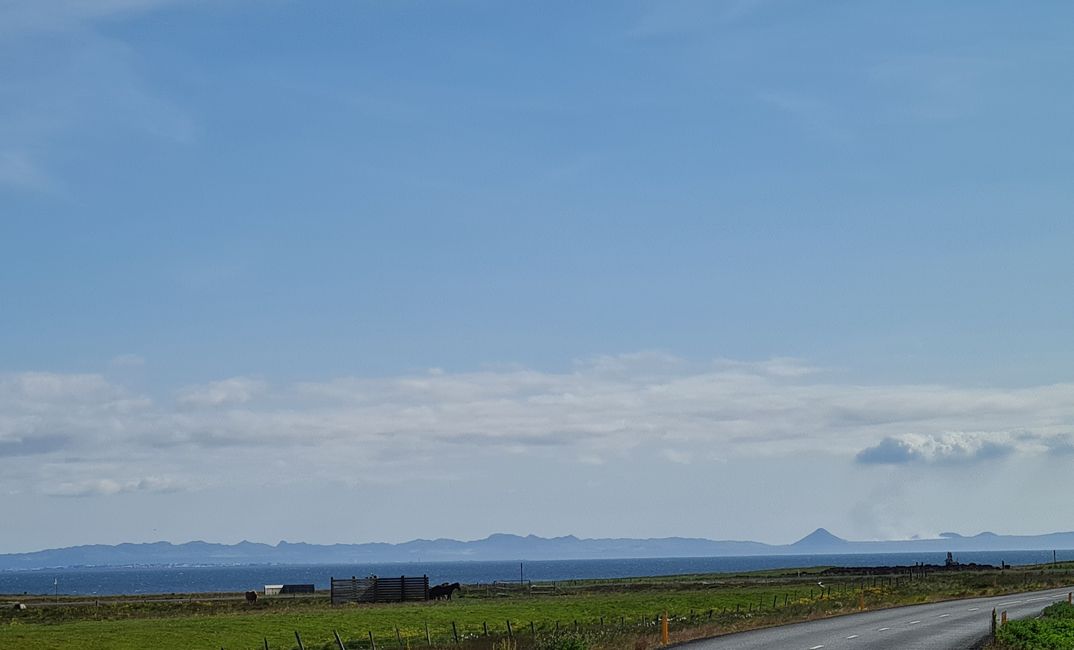 On the back right, by the cone-shaped mountain, you can see the cloud formation from the active volcano in the Geldingadalur Valley.