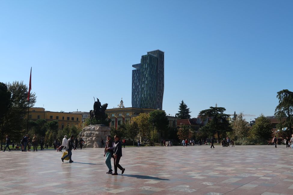 Skanderbeg-Platz, der Hauptplatz Tiranas. Er wurde über die Jahre mehrmals komplett umgestaltet. Die quadratischen Steinplatten kommen aus allen Regionen des Landes, um Einheit zu symbolisieren. Im Sommer sorgen kleine Springbrunnen für Abkühlung. 