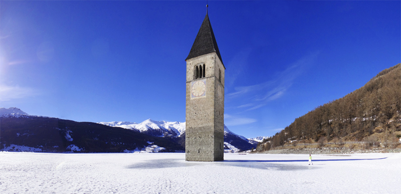 Reschensee in winter with the church tower of Graun