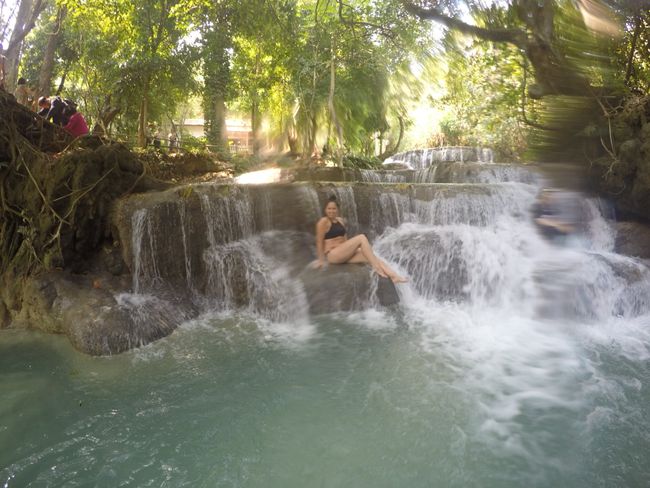Tad Kuang Si: Franzi in einem kleinen Wasserfall, auf einem großen Stein sitzend