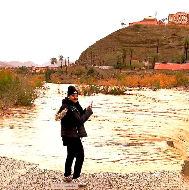 A Moroccan woman quickly takes a photo of the floods.