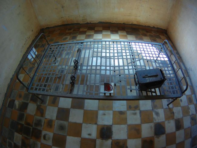 The prisoners were tied to this metal bed. They had to relieve themselves in the box. 