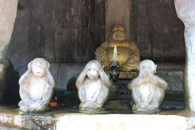 Wat Saket: Drei Affen, die Auf einem Brunnen sitzen; im Hintergrund im Inneren des Brunnens  ist ein dicker Mönch