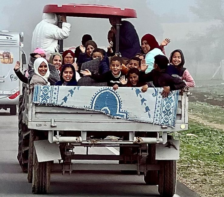 Kinder winken uns aus einem Traktor-Anhänger zu. (Foto: Birgit)