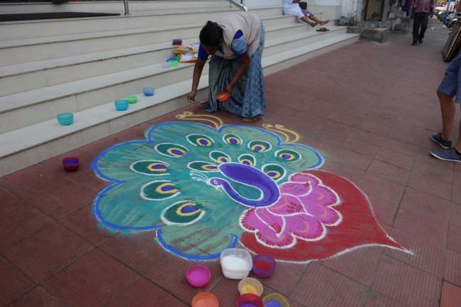 A peacock made of colored powder adorns a shop entrance for Tamil New Year