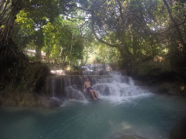 Tad Kuang Si: Joans in einem kleinen Wasserfall auf einem großen Stein sitzend