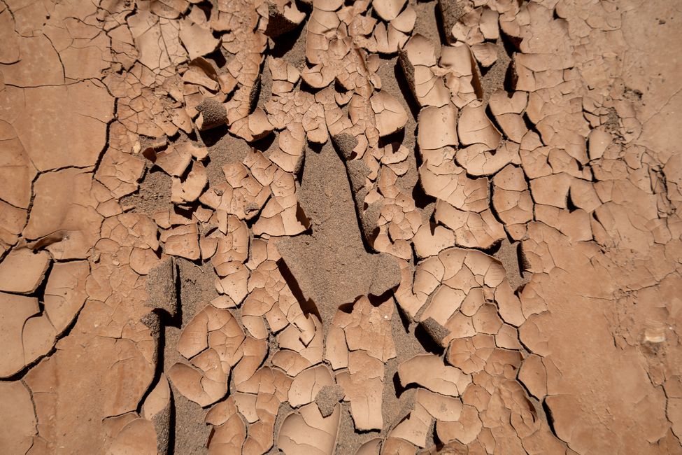 Wie Farbe von der Hauswand schält sich die Lehmschicht vom sandigen Boden