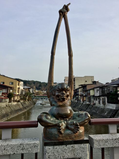 Lustige Statue auf Brücke. Die gegenüber hatte ganz lange Beine. Kommt aus einer japanischen Sage. Die Geschichte ist, dass sie beim Fischen zusammenarbeiten. Langarm sitzt auf den Schultern von Langbein, der durch das Wasser warten kann während Langarm die Fische fängt.
