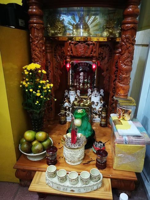 buddhistischer Geisterhäuschen mit Opfergaben in einem Touristenbüro