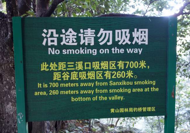 In the middle of Huang Shan mountain range: 'Smoking is not allowed on the paths. Next opportunity in one direction in 700m, in the other direction in 260m.'